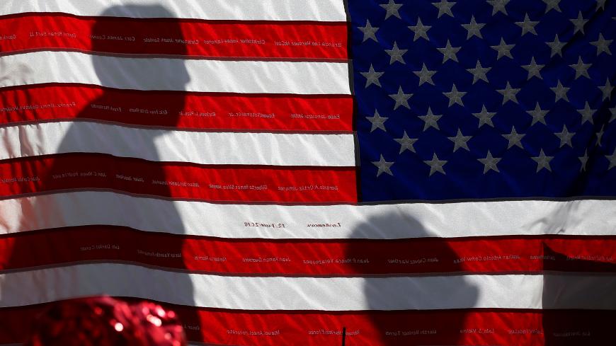 The names of Pulse night club shooting victims are embroidered on a U.S. flag at a makeshift memorial in Orlando, Florida, U.S., June 17, 2016.  REUTERS/Carlo Allegri - RTX2GV5Z