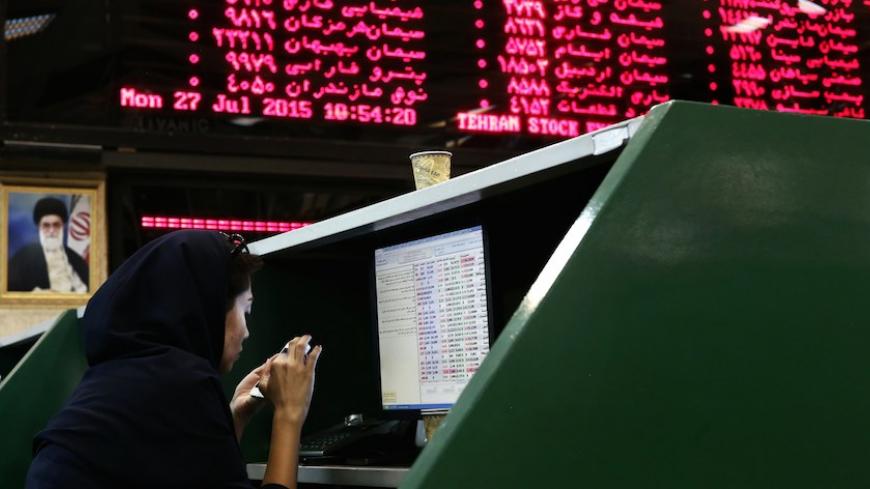 An Iranian dealer checks her mobile phone next to stock market activity boards at the stock exchange in the capital Tehran on July 27, 2015. Iran's central bank chief said that Iran has assets of $29 billion in overseas banks that could be unlocked under a nuclear deal struck on July 14, far less than reported estimates of over $100 billion. AFP PHOTO / BEHROUZ MEHRI        (Photo credit should read BEHROUZ MEHRI/AFP/Getty Images)