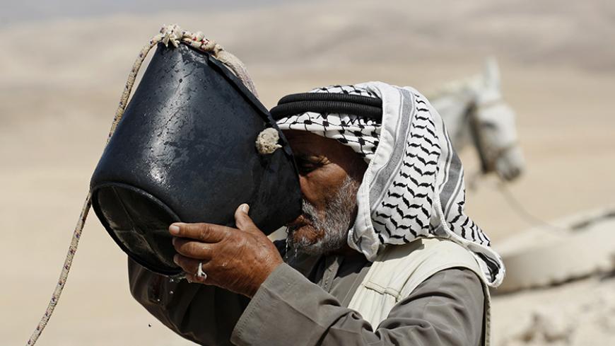 Bedouin Falah Hedawa drinks water drawn from a rainwater collection cistern in the Rashayida area, in the desert between the West Bank town of Bethlehem and the Dead Sea July 25, 2011. The cisterns which dot the desert beyond Bethlehem, many of them restored to full working order in the last few years, have for centuries harvested winter rain to provide shepherds and their flocks with water through summer. Israel has demolished 20 cisterns in the West Bank in the first half of this year, according to the U.
