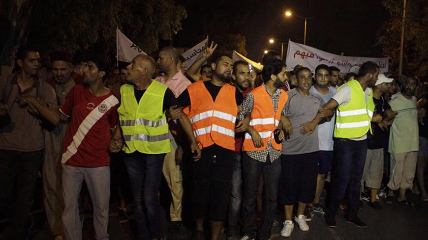 Protesters walk during a peaceful protest calling for the elimination of corruption and bribery outside the presidential palace in Carthage in Tunis August 16, 2012. REUTERS/Zoubeir Souissi (TUNISIA - Tags: POLITICS CIVIL UNREST) - RTR36WRZ