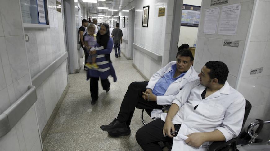 Doctors sit at the emergency reception area during a strike at Al-Moniera public hospital in Cairo October 2, 2012. Egypt's doctors began a partial strike on Monday with varied demands, including making the health budget 15 percent of the state budget, and improving security conditions to protect doctors and patients from assaults, said members of the Doctors' Syndicate. The poster on top of the wall on right reads: "An open-ended strike for doctors, For patients before doctors". REUTERS/Amr Abdallah Dalsh 