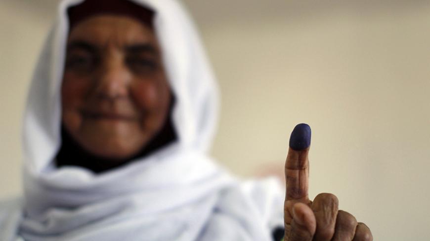 A Palestinian woman shows her ink-stained finger after casting her ballot for municipal elections at a polling station in the West Bank village of Shiyoukh, north of Hebron October 20, 2012. Palestinians voted in local elections in the Israel-occupied West Bank on Saturday, their first vote for six years and one with little choice, out of step with democratic revolutions elsewhere in the Arab world.  REUTERS/Ammar Awad (WEST BANK - Tags: ELECTIONS POLITICS) - RTR39D2R