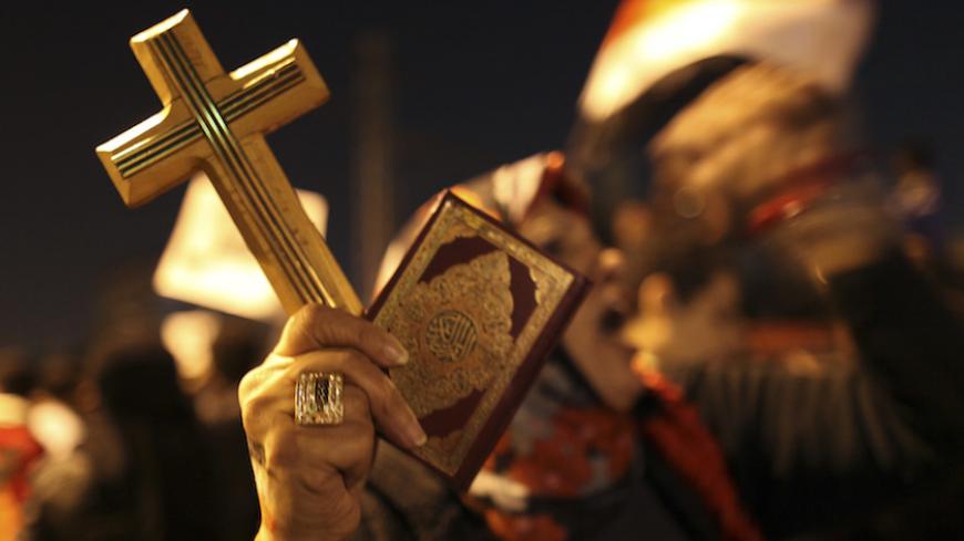 A woman holds a copy of the Koran and a cross as she shouts slogans during a demonstration against Egypt's President Mohamed Mursi in front of the presidential palace in Cairo December 18, 2012. Opponents of Mursi staged protests in Cairo on Tuesday against an Islamist-backed draft constitution that has divided Egypt but looks set to be approved in the second half of a referendum this weekend. REUTERS/Khaled Abdullah (EGYPT - Tags: POLITICS CIVIL UNREST RELIGION TPX IMAGES OF THE DAY) - RTR3BQ8Q