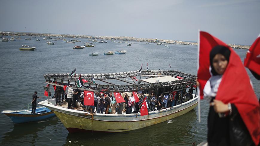 A Palestinian woman holds a Turkish flag as activists ride a boat during a rally ahead of the 4th anniversary of the Mavi Marmara Gaza flotilla incident, at the seaport of Gaza City May 29, 2014. Nine activists, eight Turkish and one Turkish-American, died on May 31, 2010, when Israeli commandos raided the Mavi Marmara ship, which was part of a flotilla seeking to break the blockade imposed on the Gaza Strip. A Turkish court issued arrest warrants on Monday for four former Israeli military commanders on tri