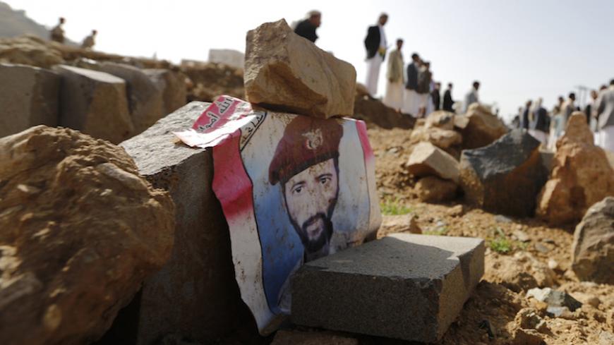 A poster with an image of a soldier lies on his grave after he was killed by al Qaeda militants in the Wadi Hadramout region in northeastern Yemen, at a military cemetery in Sanaa August 10, 2014. An al Qaeda-affiliated group in Yemen said it killed 14 soldiers in an eastern province as revenge for an army offensive against its members, while a U.S. drone attack killed three suspected militants in central Yemen on Saturday, an official said. REUTERS/Khaled Abdullah (YEMEN - Tags: POLITICS CIVIL UNREST MILIT