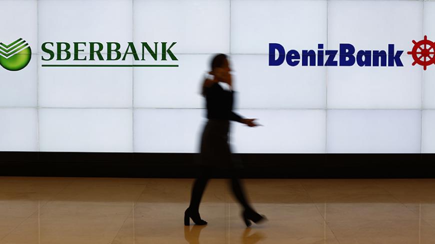 A Denizbank employee walks past by logos of Russia's Sberbank (L) and Turkey's Denizbank at Denizbank headquarters in Istanbul, Turkey March 2, 2016. REUTERS/Murad Sezer  ADCO - RTS8YUX