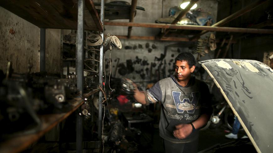 Palestinian boy Mohamoud Yazji, 16, who works as apprentice mechanic, repairs a car at a garage in Gaza City March 17, 2016. Yazji, whose father works as a tailor, earns 50 Shekels ($12.9) a week to help his father support their family. The boy, who quit school, hopes to own a garage in the future. REUTERS/Mohammed Salem  SEARCH "SALEM LABOUR" FOR THIS STORY. SEARCH "THE WIDER IMAGE" FOR ALL STORIES  - RTSCT76