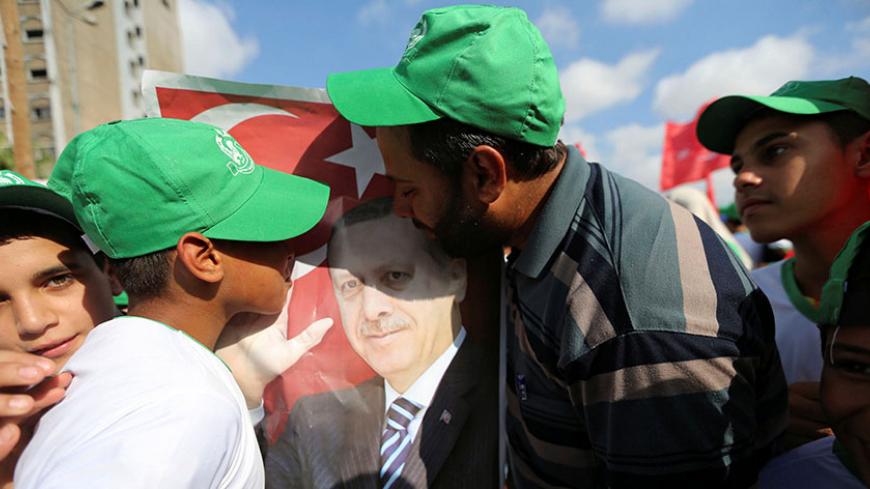 Palestinian Hamas supporters kiss a poster of Turkish President Tayyip Erdogan during a Hamas rally in support of Erdogan's government against a coup attempt, in Khan Younis in the southern Gaza Strip July 16, 2016. REUTERS/Ibraheem Abu Mustafa - RTSI91L