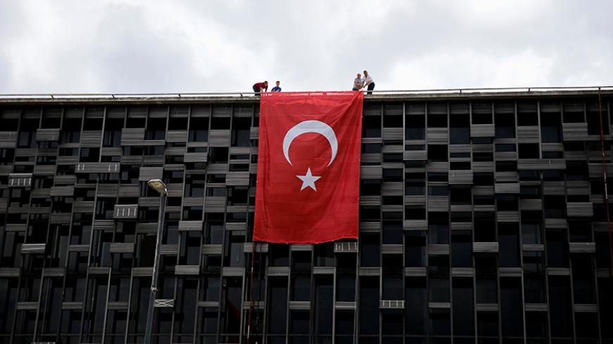 People hang a Turkish national flag on a building on Taksim square in Istanbul, Turkey, July 20, 2016. REUTERS/Alkis Konstantinidis - RTSITN7