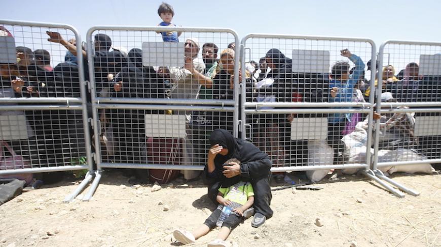 Syrian refugees wait for transportation after crossing into Turkey from the Syrian town of Tal Abyad, near Akcakale in Sanliurfa province, Turkey, June 10, 2015. REUTERS/Osman Orsal - RTX1FYOZ