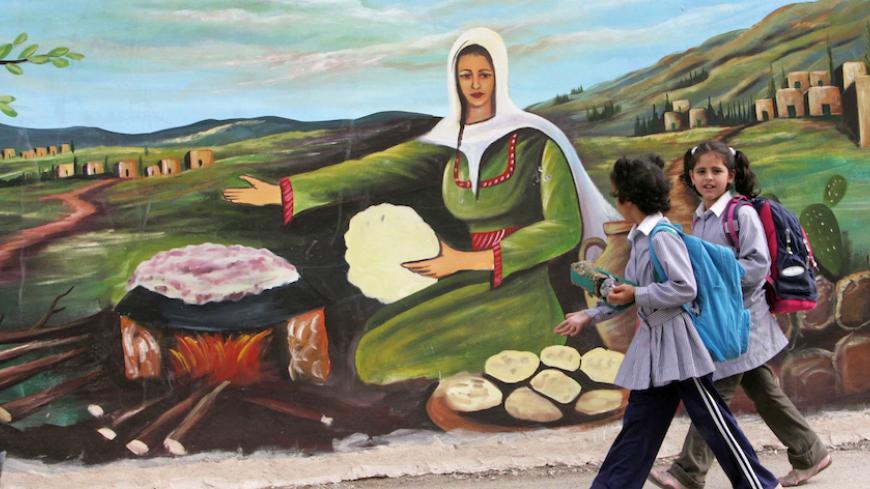 Palestinian schoolgirls walk past a mural painted on a wall in the West Bank city of Jenin November 7, 2007. REUTERS/Mohamad Torokman (WEST BANK) - RTX2BY