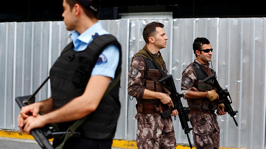 A police officer stands guard as the members of police special forces (background) patrol at Ataturk airport in Istanbul, Turkey, June 30, 2016. REUTERS/Murad Sezer  - RTX2J19T