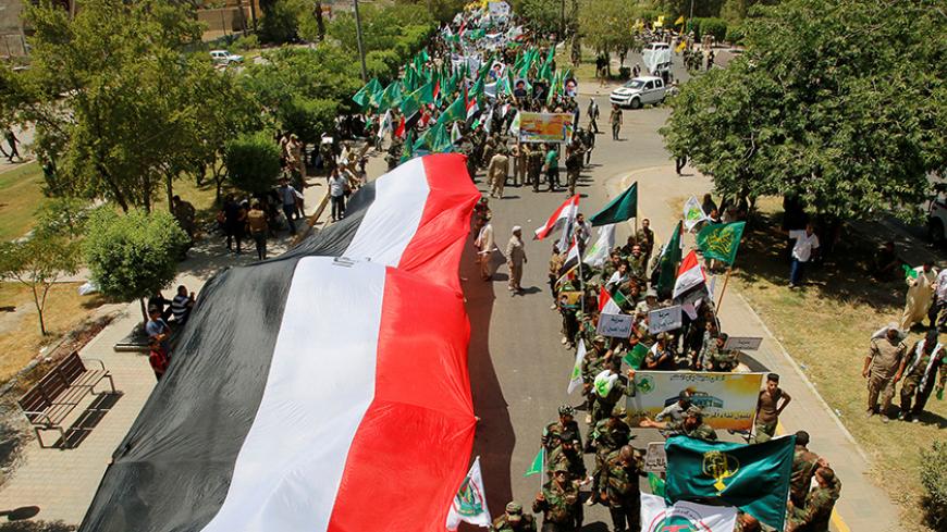 Iraqi Shi'ite Muslims from Hashid Shaabi (Popular Mobilization) march along a street as they hold a giant Iraqi flag during a parade marking the annual al-Quds Day, or Jerusalem Day, during the Muslim holy month of Ramadan in Baghdad, Iraq July 1, 2016. REUTERS/Khalid al Mousily - RTX2J7X3