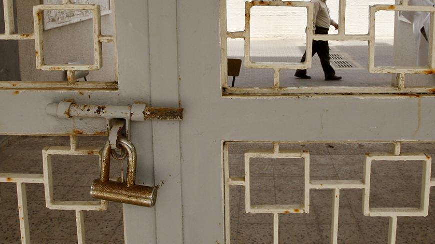 A Palestinian man walks past a closed gate of al-Aqsa University in Gaza April 15, 2008. Two major Gaza universities suspended classes on Tuesday, saying a fuel crisis in the Hamas-controlled territory was making it difficult for students to travel to school. REUTERS/Mohammed Salem (GAZA) - RTR1ZI9K
