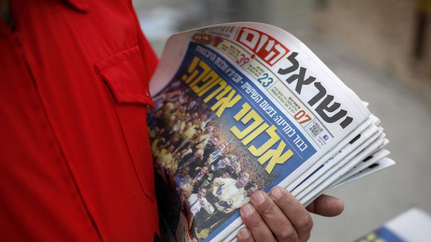 An Israeli worker for for the daily newspaper "Israel Hayom" holds copies of the newspaper as he distributes them to drivers of passing vehicles and pedestrians in Jerusalem May 19, 2014. REUTERS/Baz Ratner (JERUSALEM - Tags: POLITICS MEDIA) - RTR3PRVO