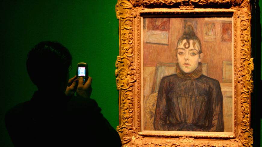 An Iranian man takes a picture of a painting by 19th century painter Henri de Toulouse-Lautrec during the Modern Art Movement exhibition at Tehran Museum of Contemporary Art in Tehran August 29, 2005. REUTERS/Morteza Nikoubazl  MN/JJ - RTRLUWV