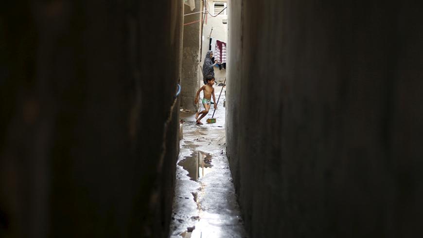 A Palestinian boy helps his mother remove the sewage water that flooded into their house during a power cut at Shatti (beach) refugee camp in Gaza City September 15, 2015. Power has been provided to different areas in the impoverished coastal territory in six-hour shifts as Gaza's lone power plant shut its generators on Saturday due to a fuel shortage, energy officials said. Electricity is also supplied to the Gaza grid through power lines from Israel and Egypt. Gaza's plant provides electricity to two-thir