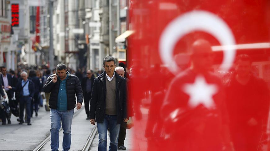 People stroll at Istiklal street, a major shopping and tourist district, in central Istanbul, Turkey March 22, 2016. A Turkish flag, which is placed on the stall of a street vendor, is seen on the right.  REUTERS/Osman Orsal  - RTSBZAH