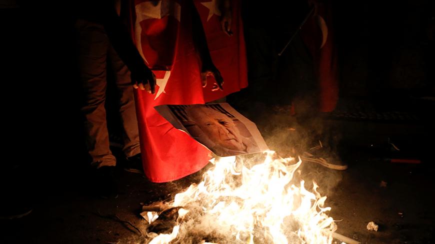 A supporter of Turkish President Tayyip Erdogan prepares to burn a photo of U.S.-based cleric Fethullah Gulen during a pro-government demonstration on Taksim Square in Istanbul, Turkey, July 18, 2016. REUTERS/Alkis Konstantinidis - RTSILD0