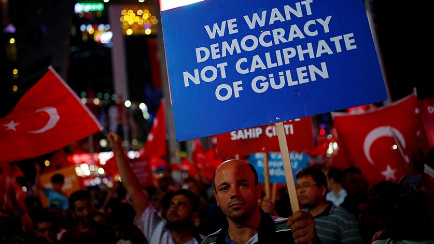 A man holds a banner as he and others have gathered in solidarity night after night since the July 15 coup attempt in central Ankara, Turkey, July 27, 2016. REUTERS/Umit Bektas - RTSJZ30