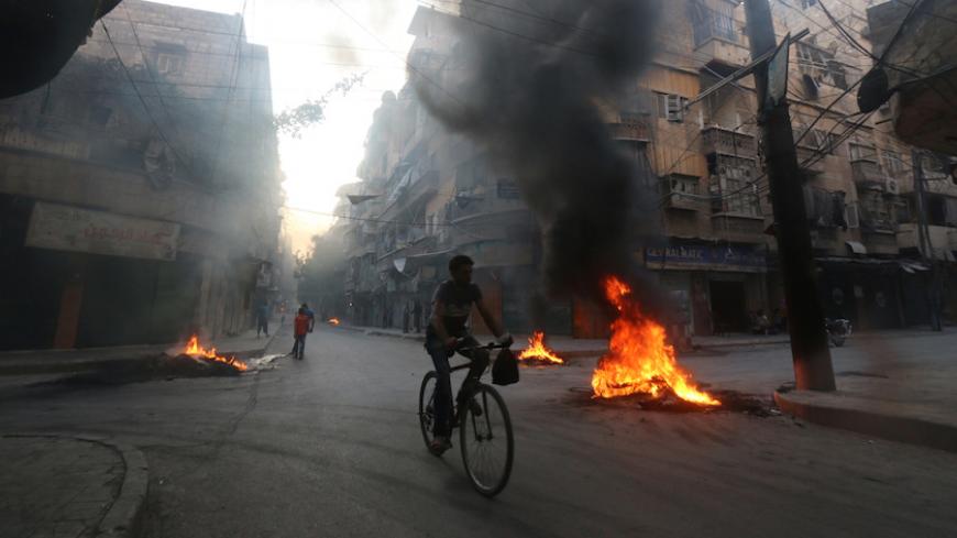 A man rides a bicycle past burning tyres, which activists said are used to create smoke cover from warplanes, in Aleppo, Syria  August 1, 2016. REUTERS/Abdalrhman Ismail - RTSKLM0