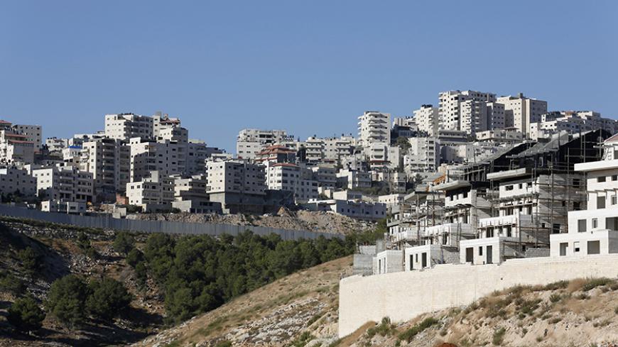 A construction site is seen in Pisgat Zeev (R), an urban settlement in an area Israel annexed to Jerusalem after capturing it in the 1967 Middle East war, as the Shuafat refugee camp (rear) in the West Bank is seen behind a section of the controversial Israeli barrier, July 28, 2013. Prime Minister Benjamin Netanyahu on Sunday urged divided rightists in his cabinet to approve the release of 104 Arab prisoners in order to restart peace talk with the Palestinians. The prisoner release would allow Netanyahu to