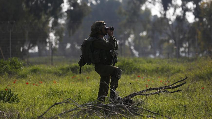 An Israeli soldier uses his binoculars as he looks towards the northern part of the Israeli Gaza border in southern Israel January 13, 2016. An Israeli aircraft attacked a group of Palestinians in the Gaza Strip on Wednesday who the military said planned to detonate a bomb at the border with Israel, and a Palestinian militant faction said one of its men was killed. REUTERS/Amir Cohen   - RTX227Q4