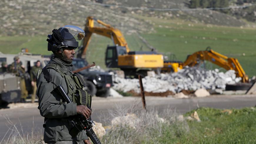 An Israeli border policeman stands guard during the demolition of a Palestinian house under the order of the Israeli army, in the West Bank town of Dura, south of Hebron January 20, 2016. The owners of the house said they were informed by the Israeli army that the demolition was carried out because they did not have an Israeli-issued construction permit. REUTERS/Mussa Qawasma  - RTX236ZL