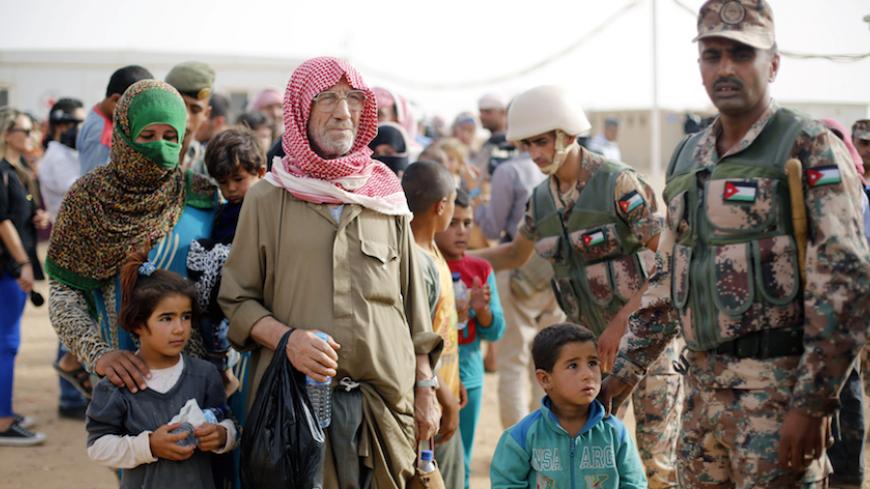 Syrian refugees wait to board a Jordanian army vehicle after crossing into Jordanian territory with their families, in Al Ruqban border area, near the northeastern Jordanian border with Syria, and Iraq, near the town of Ruwaished, 240 km (149 miles) east of Amman September 10, 2015. Picture taken September 10, 2015. REUTERS/Muhammad Hamed - RTX2II4S