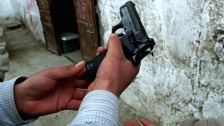 Palestinian teenagers handle a nine millimeter semi-automatic pistol in the Dheisheh refugee camp in Bethlehem January 4, 2001. The Dheisheh refugee camp hosts thousands of Palestinian refugees since the 1948 Israeli occupation. [Palestinian leader Yasser Arafat began consulting Arab leaders in Cairo on Thursday on U.S. President Bill Clinton's peace proposals before announcing whether he accepts them.   ] - RTXK7RJ