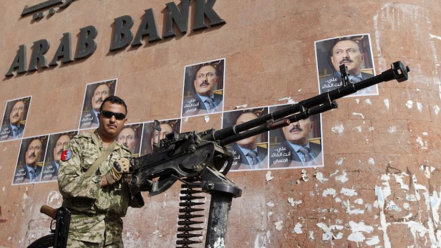 A soldier loyal to Yemen's former President Ali Abdullah Saleh (in posters) holds a machine gun mounted on a patrol truck securing a street near a rally held by Saleh's supporters to mark one year of Saudi-led air strikes in Yemen's capital Sanaa March 26, 2016. REUTERS/Khaled Abdullah - RTSCB4F