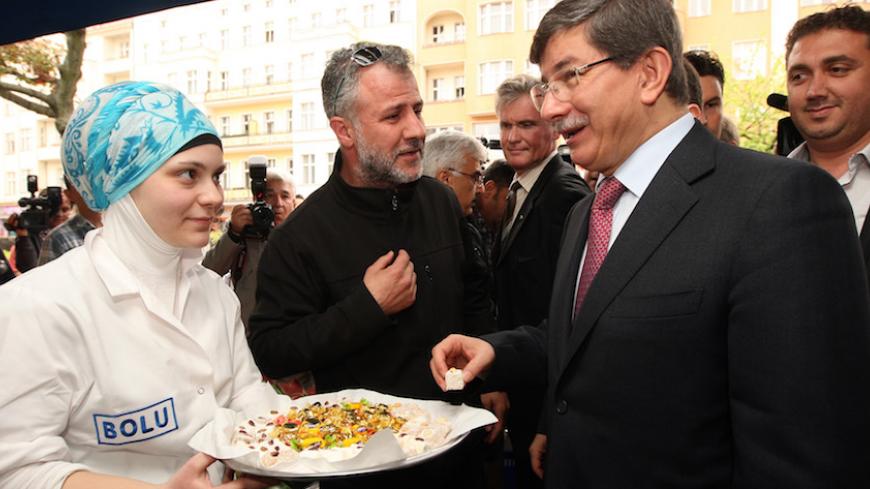 Turkish Foreign Minister Ahmet Davutoglu (R) tries a piece of Turkish delight, "lokum", as he visits members of the Turkish community in the Kreuzberg neighborhood in Berlin on May 11, 2013.  AFP PHOTO / ADAM BERRY        (Photo credit should read ADAM BERRY/AFP/Getty Images)
