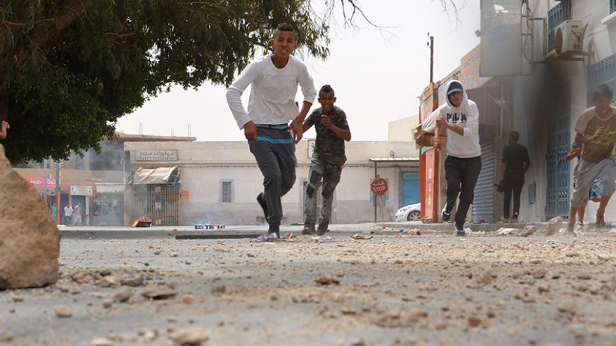 Tunisians boys run away as they throw stones towards the police station on May 11, 2016 in the Tunisian southern border town of Ben Guerdane, as the town went on strike in protest at a decision by Libyan authorities late last month to halt cross-border trade on which its economy depends. 
Ben Guerdane is one of the North African nation's poorest towns and has also been hit by jihadist violence from across the border that killed seven civilians and 13 security personnel in March as well as 55 extremists. Onl
