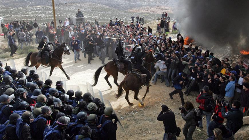 Israeli policemen clash with Jewish settlers at a burning barricade in the unauthorized outpost of Amona, close to the West Bank Jewish settlement of Ofra, February 1, 2006. Israeli riot police clashed on Wednesday with several thousand settlers battling to block partial demolition of an unauthorised West Bank outpost in scenes reminiscent of Israel's Gaza pullout. REUTERS/Oleg Popov - RTR19FRI