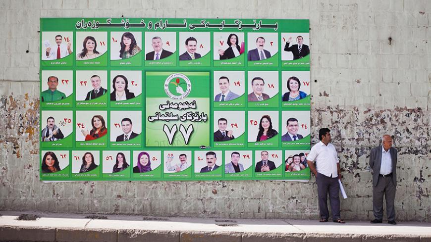 Men stand next to a Patriotic Union of Kurdistan (PUK) campaign poster for Iraq's parliamentary elections in Sulaimaniya April 28, 2014. Picture taken April 28, 2014.        To match IRAQ-ELECTION/KURDS      REUTERS/Jacob Russell (IRAQ - Tags: ELECTIONS POLITICS) - RTR3N0GT