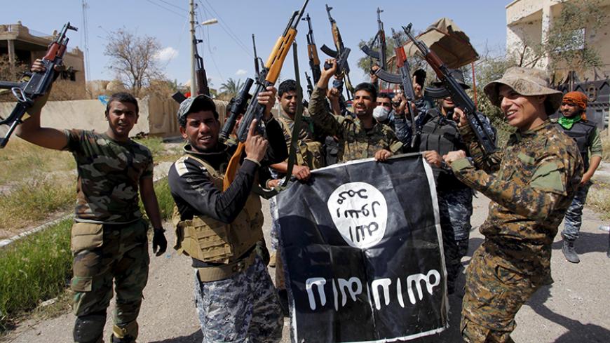 Iraqi security forces and Shi'ite paramilitary fighters hold an Islamist State flag, which they pulled down in Tikrit, March 31, 2015. Iraqi troops aided by Shi'ite paramilitaries and Sunni tribal fighters have reached the center of Tikrit after securing the Sunni city's southern and western sections from Islamic State militants, Prime Minister Haidar al-Abadi said on Tuesday. "Our security forces have reached the center of Tikrit and they have liberated the southern and western sides and they are moving to