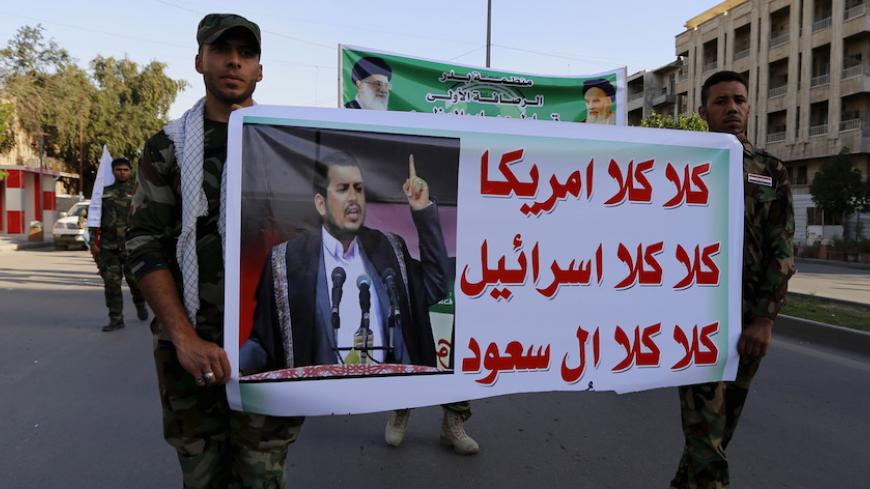 Member from Hashid Shaabi hold a banner of Abdulmalik al-Huthi during a demonstration to show support for Yemen's Shi'ite Houthis and in protest of an air campaign in Yemen by a Saudi-led coalition, in Baghdad March 31, 2015. Saudi troops clashed with Yemeni Houthi fighters on Tuesday in the heaviest exchange of cross-border fire since the start of a Saudi-led air offensive last week, while Yemen's foreign minister called for a rapid Arab intervention on the ground. REUTERS/Thaier Al-Sudani - RTR4VNMI