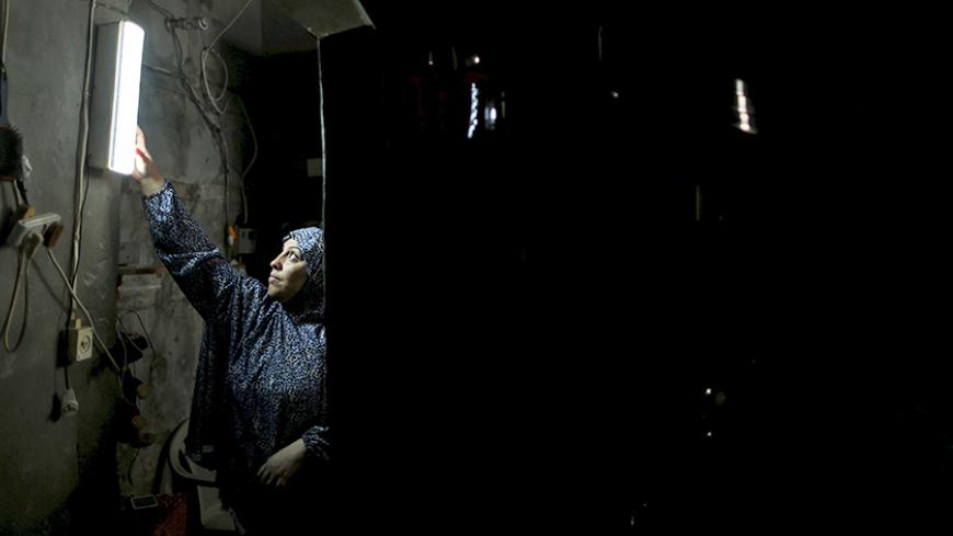 A Palestinian woman hangs a torch inside her house during power cuts at Shatti (beach) refugee camp in Gaza City September 15, 2015. Power has been provided to different areas in the impoverished coastal territory in six-hour shifts as Gaza's lone power plant shut its generators on Saturday due to a fuel shortage, energy officials said. Electricity is also supplied to the Gaza grid through power lines from Israel and Egypt. Gaza's plant provides electricity to two-thirds of its population. REUTERS/Mohammed 