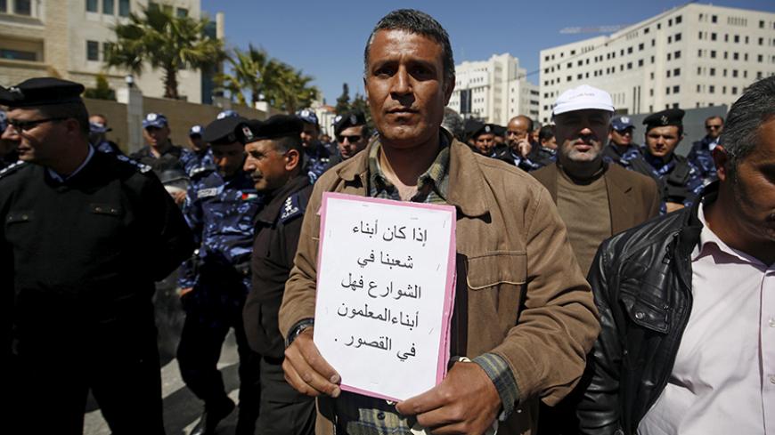 A Palestinian teacher holds a sign during a protest demanding better pay and conditions, in the West Bank city of Ramallah March 7, 2016. For a month, more than 25,000 teachers in the West Bank have been on strike over pay and benefits, causing chaos for schools, pupils and parents, and prompting the Palestinian Authority to deploy military police on the streets of Ramallah. The sign reads, "If the sons of our people are in the streets, are the teachers' sons in palaces?". Picture taken March 7. REUTERS/Moh