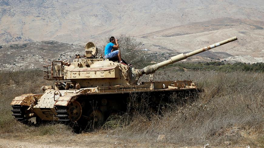 A man sits on an old tank as he watches fighting taking place in Syria as seen from the Israeli side of the border fence between Syria and the Israeli-occupied Golan Heights September 11, 2016. REUTERS/Baz Ratner - RTSN7X9