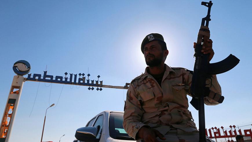 A member of Libyan forces loyal to eastern commander Khalifa Haftar holds a weapon as he sits on a car in front of the gate at Zueitina oil terminal in Zueitina, west of Benghazi, Libya September 14, 2016. Picture taken September 14, 2016. REUTERS/Esam Omran Al-Fetori - RTSNU2U
