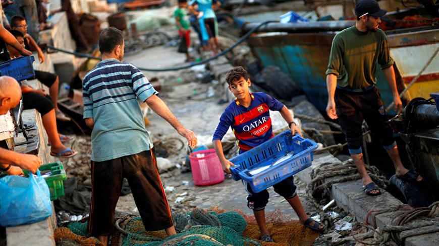 A Palestinian boy carries a container containing fish as he works with fishermen at the seaport of Gaza City September 26, 2016. Picture taken September 26, 2016. REUTERS/Mohammed Salem - RTSPO9E