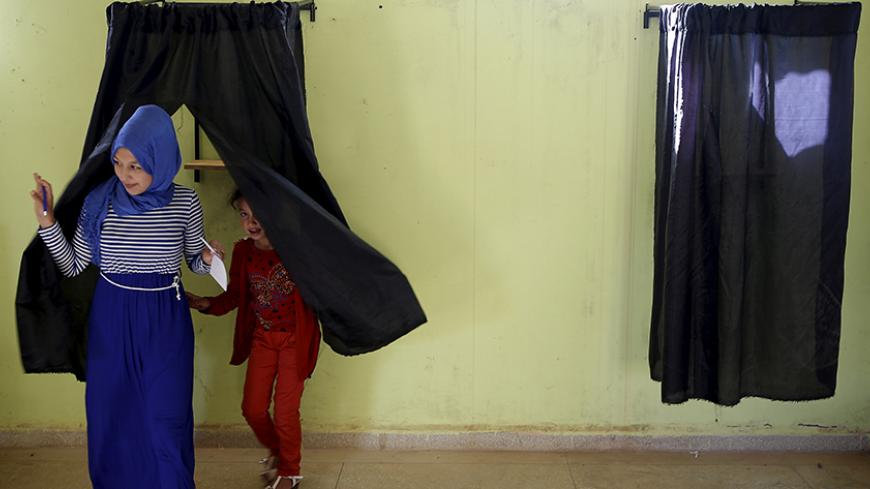 A woman (L) leaves a booth before casting her ballot at a polling station in the town of Tifelt, east of Rabat, Morocco September 4, 2015. Morocco's ruling Islamist party on Friday faced a major test of its dominance as polls opened for local elections for which most opposition parties have campaigned on anti-corruption platforms and against privileges for the elite. REUTERS/Youssef Boudlal      TPX IMAGES OF THE DAY      - RTX1R65C