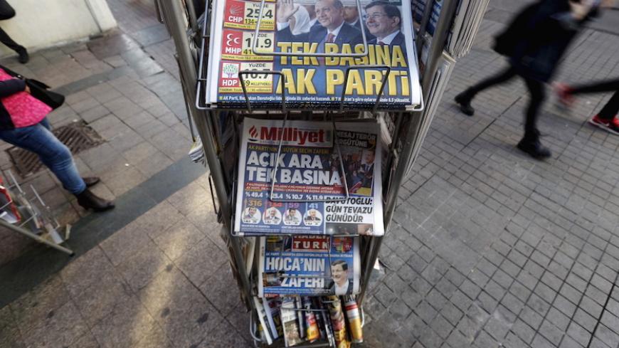 People walk past by a kiosk in central Istanbul, Turkey November 2, 2015. A jubilant President Tayyip Erdogan on Monday cast the return of Turkey's Islamist-rooted AK Party to single-party rule as a vote for stability that the world must respect, but opponents fear it heralds growing authoritarianism and deeper polarisation. The newspaper headline on top reads: "AK Party on its own" REUTERS/Murad Sezer  - RTX1UE7G