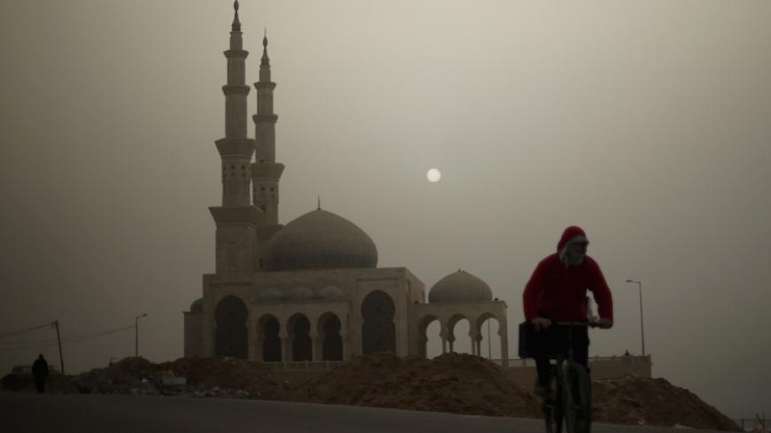 A Palestinian man rides his bicycle in front of a mosque on a stormy day in Gaza January 18, 2016. REUTERS/Mohammed Salem  - RTX22XLX