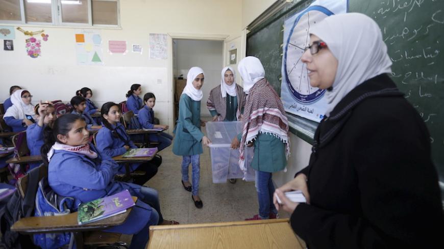 A teacher distributes meals to students as part of a World Food Programme (WFP)-run project to provide healthy meals to students and to raise awareness of good eating habits, at Hofa Al-Mazar school  in the city of Irbid, Jordan, April 26, 2016. REUTERS/ Muhammad Hamed - RTX2BQMO