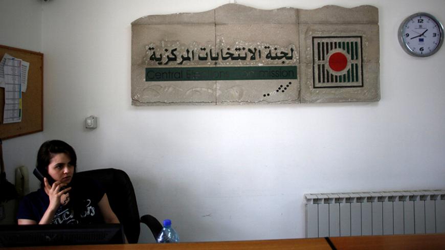 A Palestinian employee speaks on the phone in the office of the Central Elections Commission in the West Bank town of El Bireh August 17, 2016. REUTERS/Mohamad Torokman  - RTX2LI4S