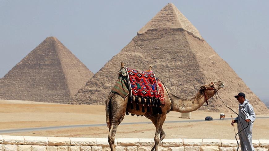 A man waits for tourists to rent his camel in front of the Great Giza pyramids on the outskirts of Cairo, Egypt, August 31, 2016. Picture taken August 31, 2016. REUTERS/Mohamed Abd El Ghany - RTX2NS62