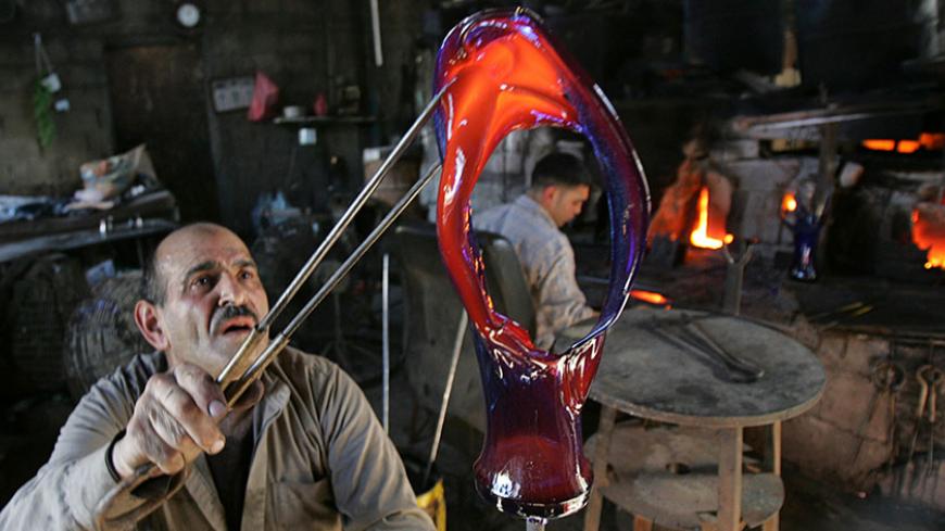 A Palestinian man holds up a vase in a glass factory in the West Bank city of Hebron December 15, 2007. Picture taken December 15, 2007. REUTERS/Nayef Hashlamoun (WEST BANK) - RTX4SNC