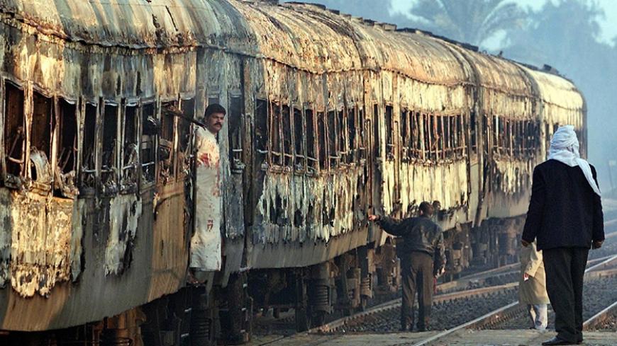 Egyptian rail road workers stand beside a train which caught fire about 80 kilometers (50 miles) south of Cairo February 20, 2002. Around 50 Egyptians trapped in a burning passenger train died in the inferno south of Cairo overnight. - RTXL2VJ